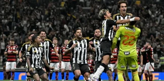 Observado pelos jogadores do Flamengo ao fundo, jogadores do Atlético-MG comemoram a classificação na Copa do Brasil