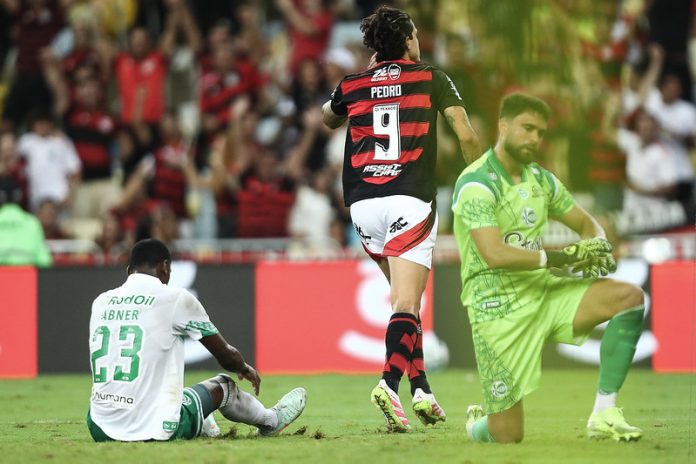 Pedro comemora, enquanto o zagueiro Abner fica no chão, na vitória do Flamengo sobre o Juventude