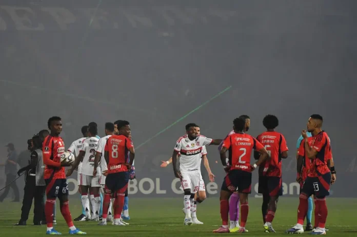 Jogadores de Flamengo e Independiente Medellín em campo durante partida paralisada da Libertadores - Foto: Jaime Saldarriaga / AFP